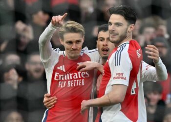 Arsenal football players in action during a match, celebrating a goal.